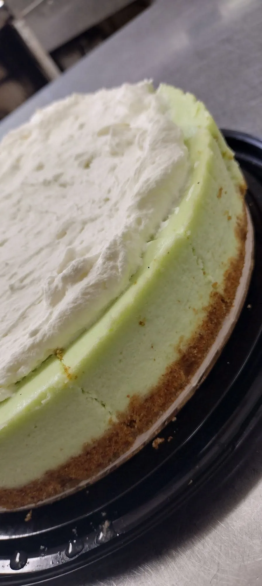 A whole key lime cheesecake topped with whipped cream on a graham cracker crust